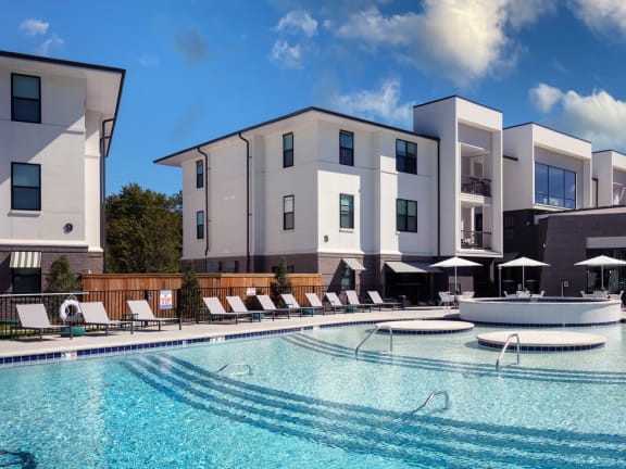 a swimming pool at night with a sunset in the background at Esplanade District Apartments, Little Rock