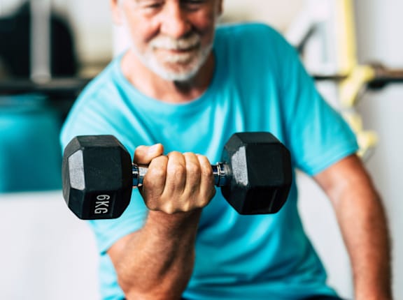 A man in a blue shirt is lifting a black dumbbell.