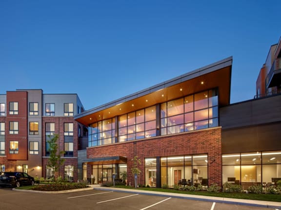 A modern multi-story building with a parking lot in front.