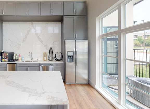 a kitchen with gray cabinets and a marble counter top