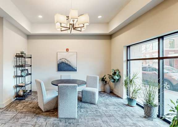 A room with a round table and chairs, a shelf, and a painting on the wall.