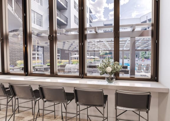 Resident Clubhouse with Table Workspace and Chairs next to Pool Views and Grill at Link Apartments® Fitz, Aurora