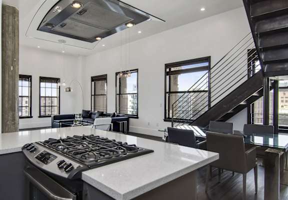 A modern kitchen with a stove top oven and a staircase.