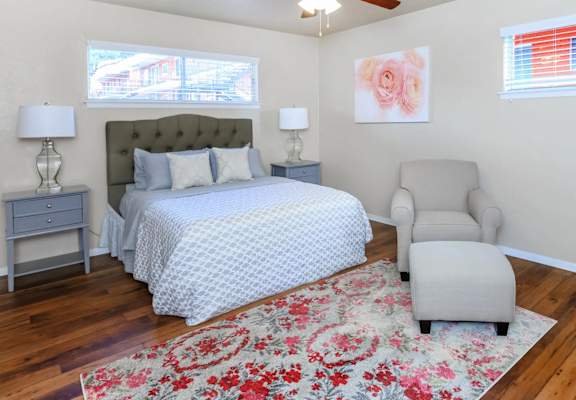 a bedroom with a bed and a chair and a rug