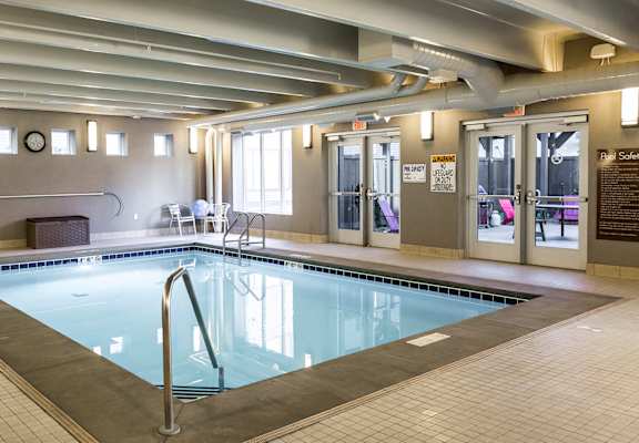 a swimming pool in the middle of a room with chairs and a table