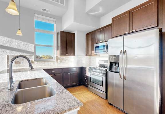 A modern kitchen with a stainless steel refrigerator and a marble countertop.