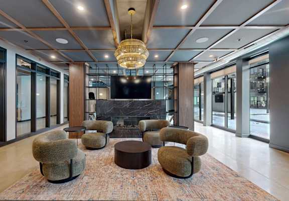 A large room with a fireplace and a rug in the middle. at Ardor on the Bluffs South Loop Residences Apartments, Bloomington, 55425