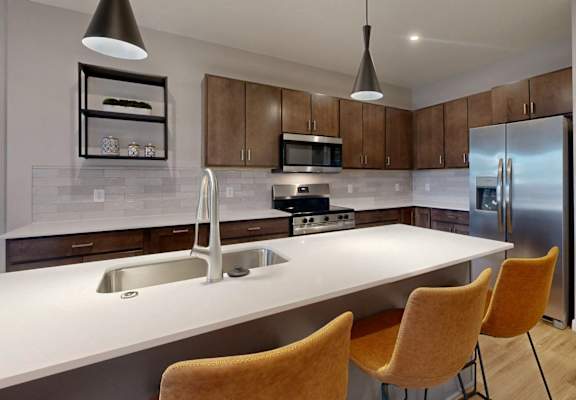 A kitchen with a white countertop and a stainless steel refrigerator. at Ardor on the Bluffs South Loop Residences Apartments, Bloomington, 55425
