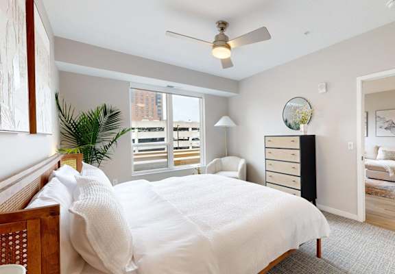 A bedroom with a large bed and a ceiling fan. at Ardor on the Bluffs South Loop Residences Apartments, Bloomington, 55425