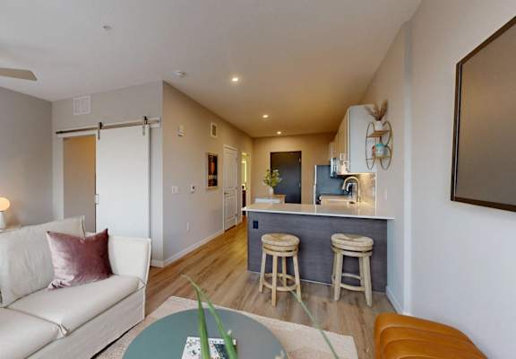 A living room with a white couch and a bar area. at Ardor on the Bluffs South Loop Residences Apartments, Bloomington, 55425