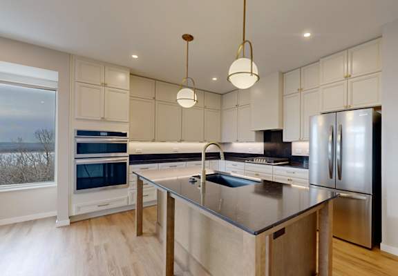 A modern kitchen with stainless steel appliances and wooden floors.