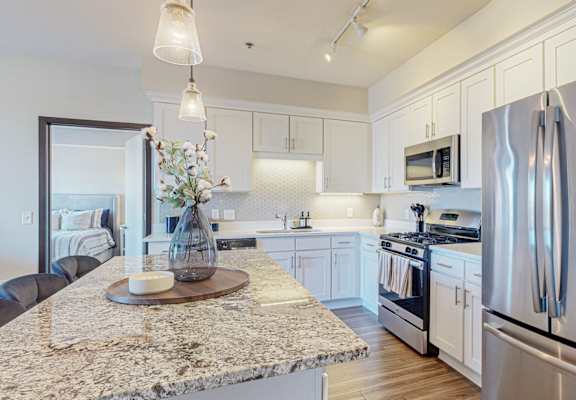 A modern kitchen with a granite countertop and stainless steel appliances.