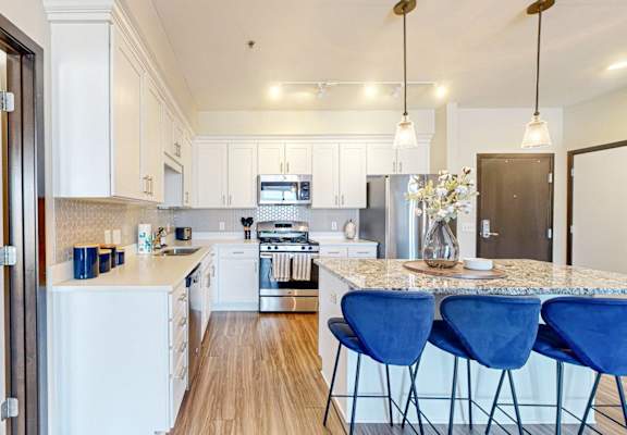 A kitchen with white appliances and blue chairs.