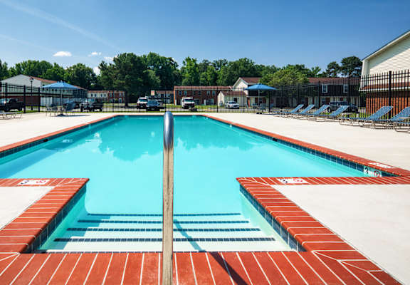 A large outdoor swimming pool with red brick lining.