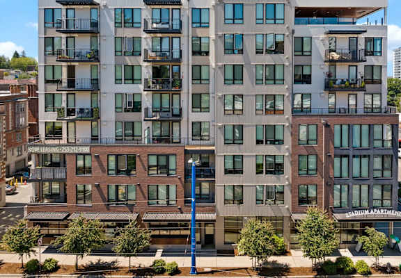 A modern apartment building with balconies and a parking lot in front.
