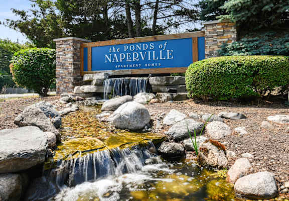 a waterfall in front of a sign for the ponds of naperville