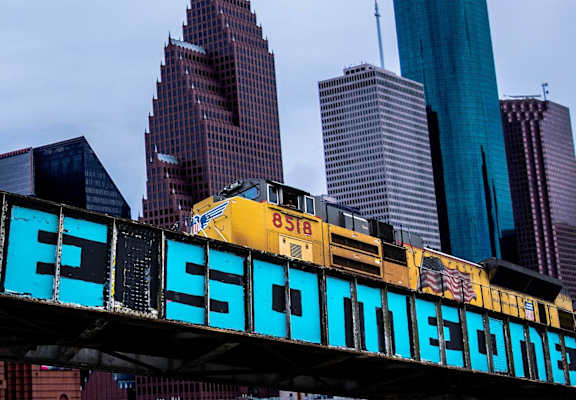 a train traveling over a bridge in front of tall buildings