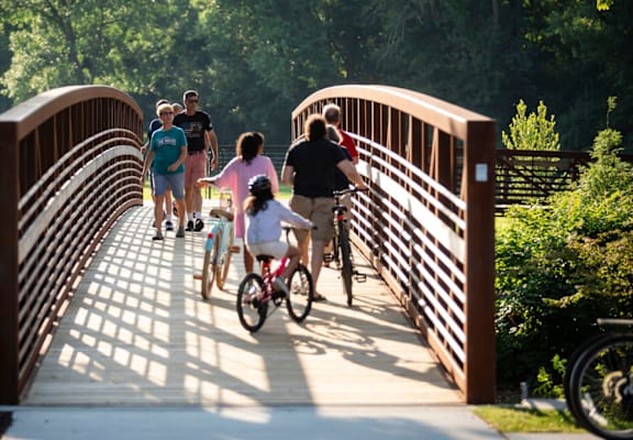 A group of people are walking across a bridge with bicycles.
