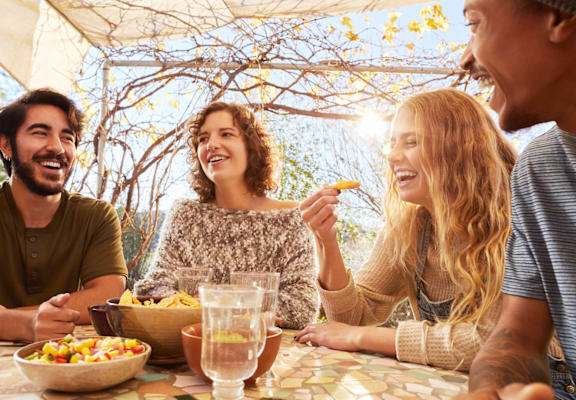 Four people are sitting at a table outdoors, enjoying a meal together.