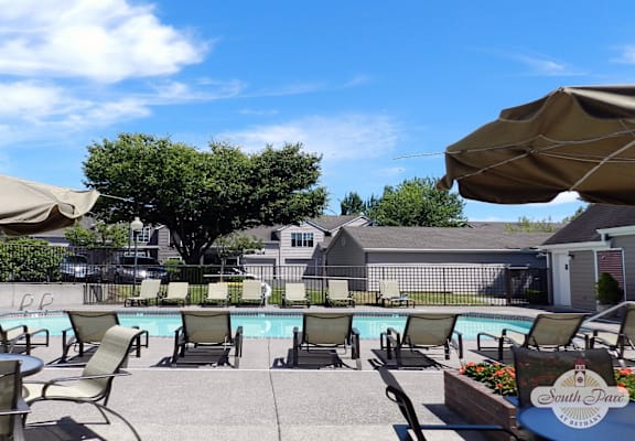 a swimming pool with chairs and umbrellas on a patio