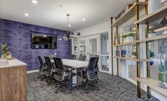 A conference room with a purple wall and a wooden bookshelf.