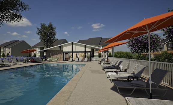 A pool with chairs and umbrellas is surrounded by buildings.