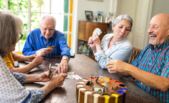 a group of people playing cards at a table with a birthday cake
