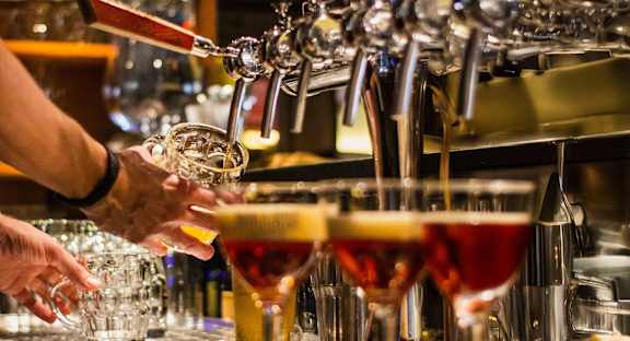 A bartender pouring drinks from a tap