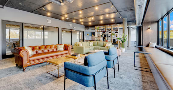 A living room with a brown leather sofa and blue chairs.
