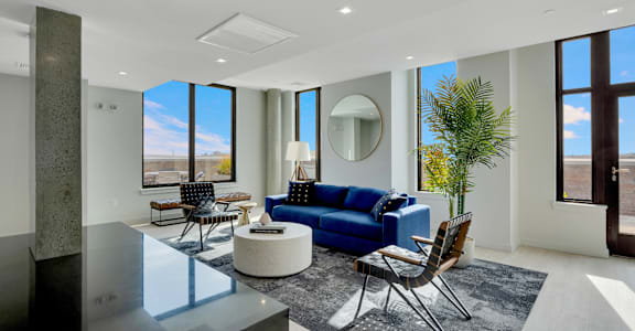 A modern living room with a blue sofa and a glass table.