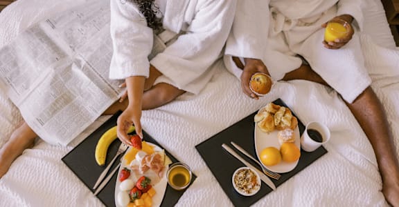 Two people in bathrobes having breakfast in bed.