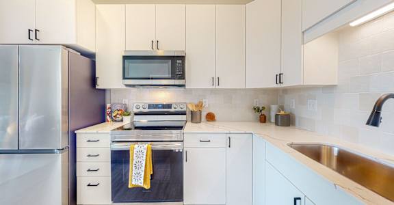 A modern kitchen with white cabinets and a stainless steel refrigerator.
