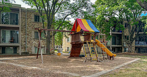 A playground with a yellow slide and a red, white, and blue canopy.