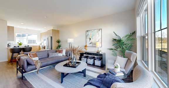 A modern living room with a grey sofa, a coffee table, and a large window.