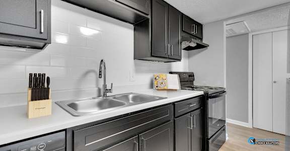A modern kitchen with black cabinets and a white countertop at 46Eleven Apartments, Dallas, TX, 75228