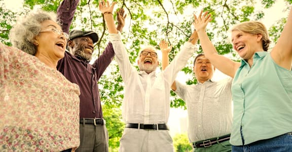 A group of people are standing together with their arms raised.