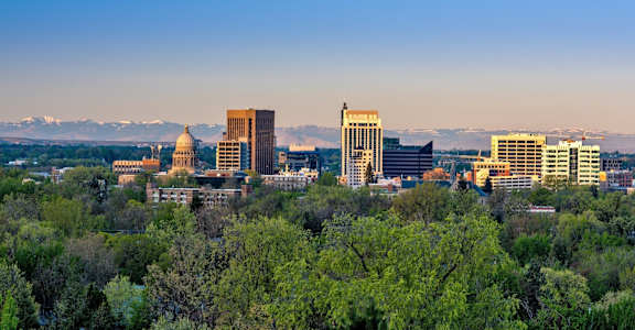 A cityscape with a mountain range in the background and a large building with a golden dome in the foreground.