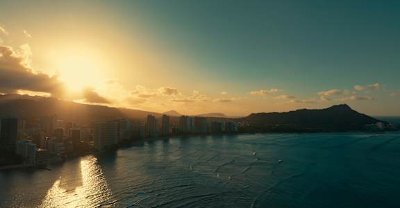 A cityscape with buildings and a body of water under a sunset.