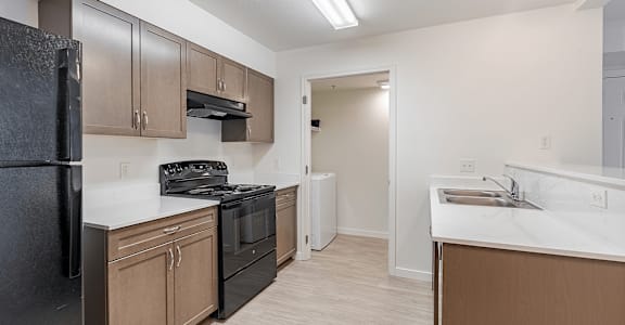 A kitchen with black appliances and brown cabinetsmat Falls Creek Apartments in Coeur d'Alene, Idaho