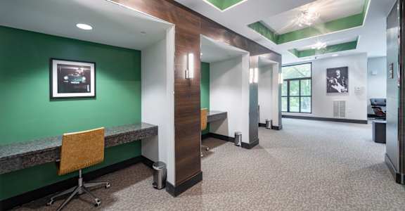 a hallway with a green wall and a desk with a chair at The Hendrix, Atlanta, GA, 30329