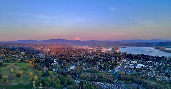 A cityscape with a mountain in the background and a body of water in the foreground.