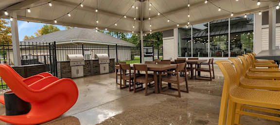a patio with tables and chairs and a grill
