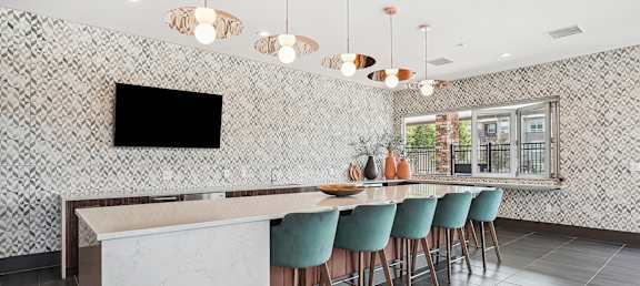 a kitchen with a long bar with blue chairs and a television