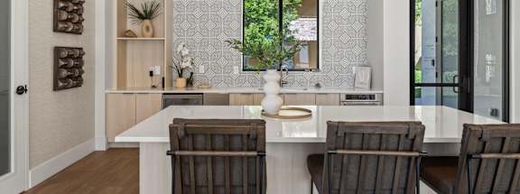 A kitchen with a white counter and brown chairs.