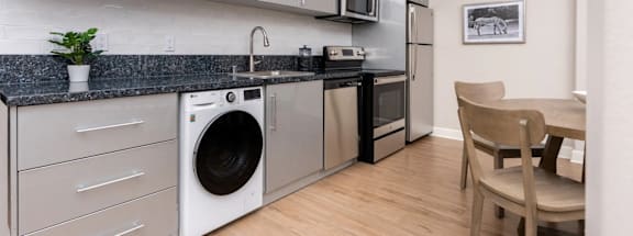a kitchen with a washer and dryer and a dining room table with chairs