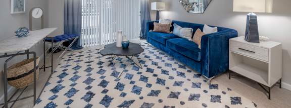 A blue sofa sits in a living room with a patterned rug.