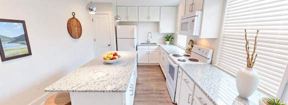 A kitchen with white cabinets and a granite countertop.