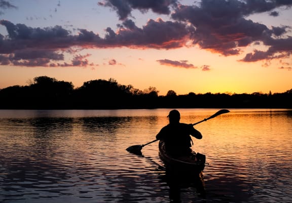 a man in a kayak on a lake at sunset