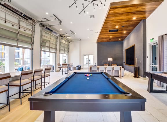 a pool table in the lobby of a building with tables and chairs
