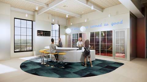 A group of people are gathered around a table in a room with a sign that says "What's brewed is steamed so good".